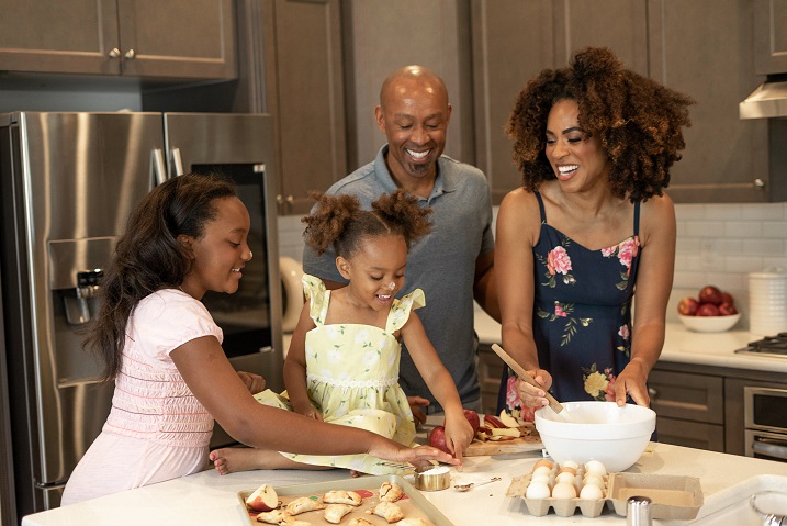 black mom and dad cooking with two daughters in the kitchen