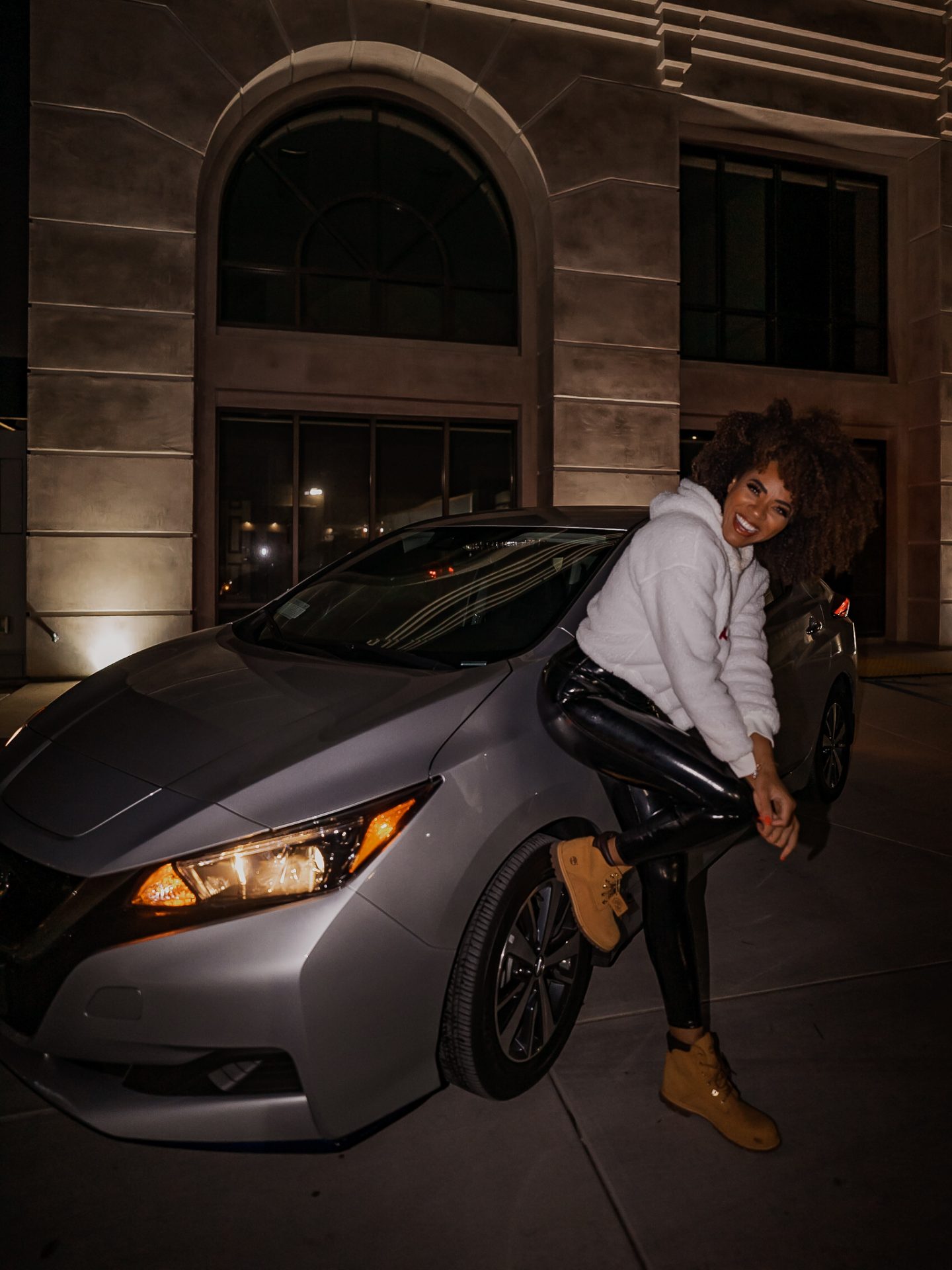 Girl leaning on Nissan Leaf